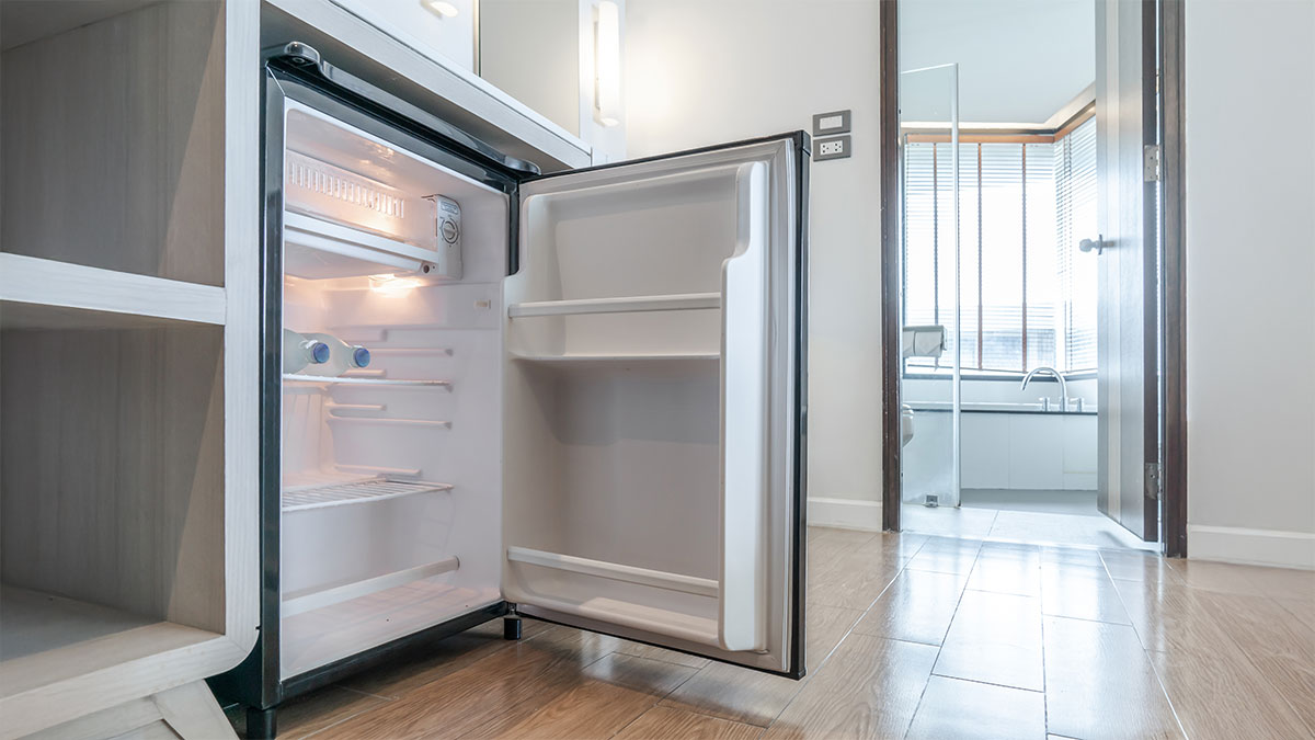 Frigorífico pequeno instalado debaixo da bancada numa cozinha luminosa